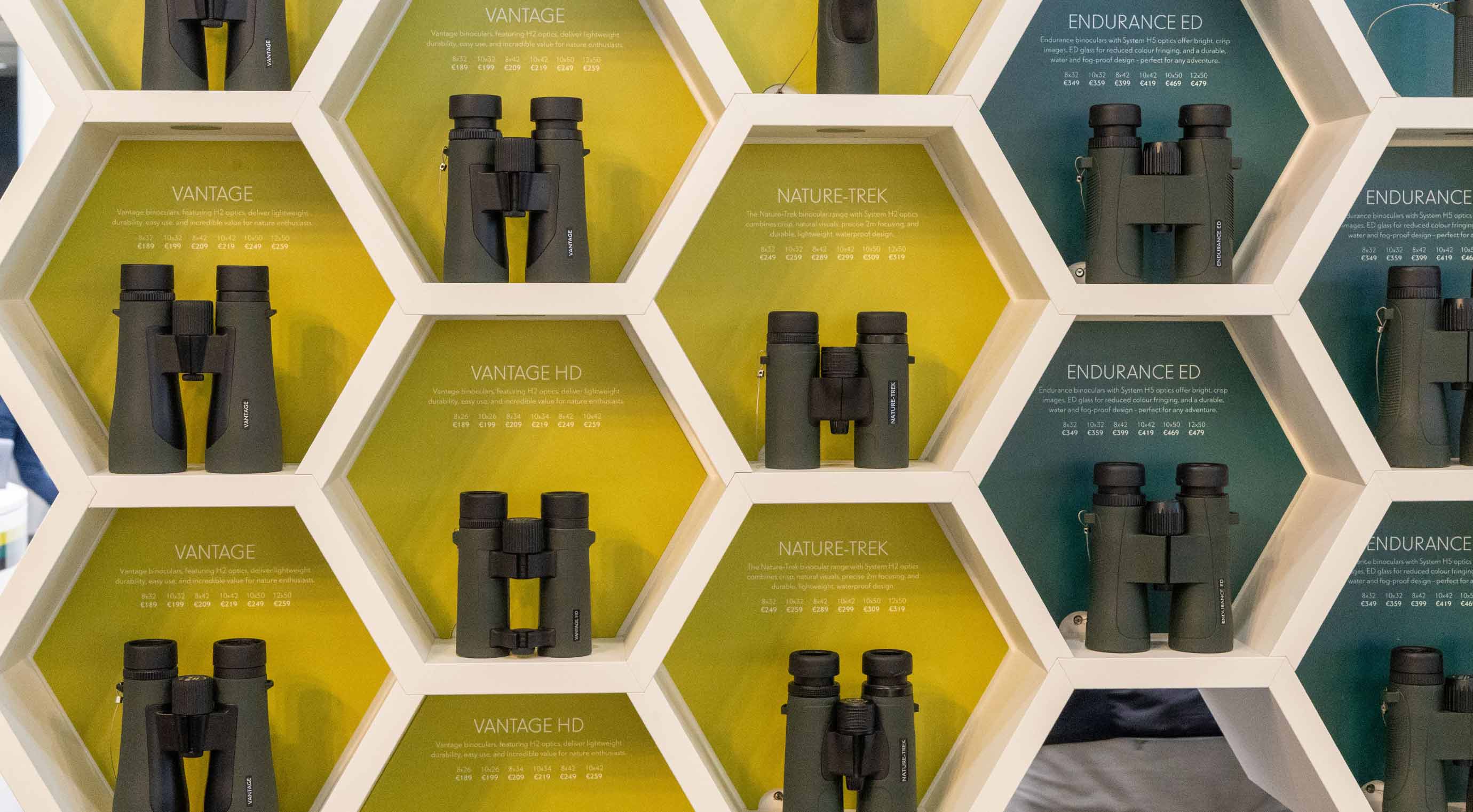 Binoculars on a white shelf in front of colourful backgrounds in shades of yellow and green.